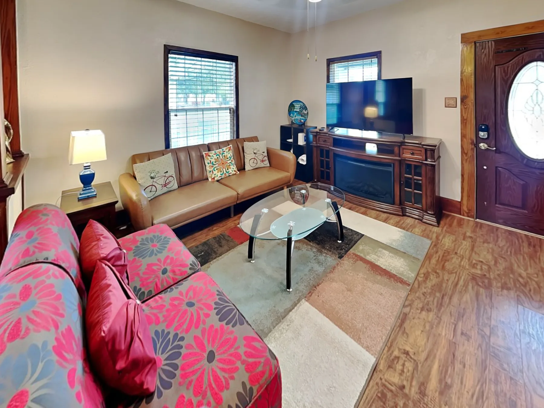 A living room with seating, a glass coffee table, and a television.
