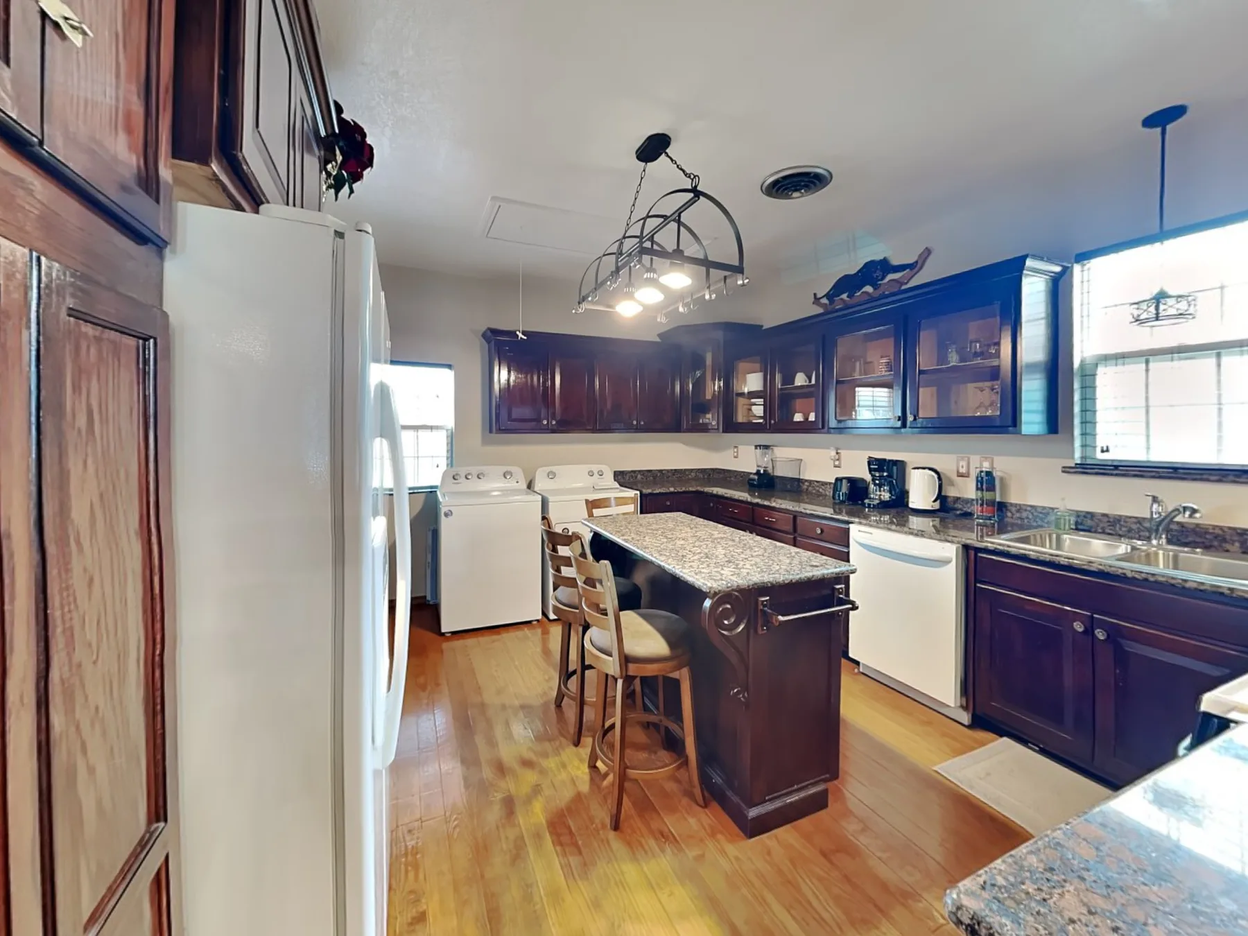 Una cocina con gabinetes de madera oscura, una isla central y electrodomésticos blancos.