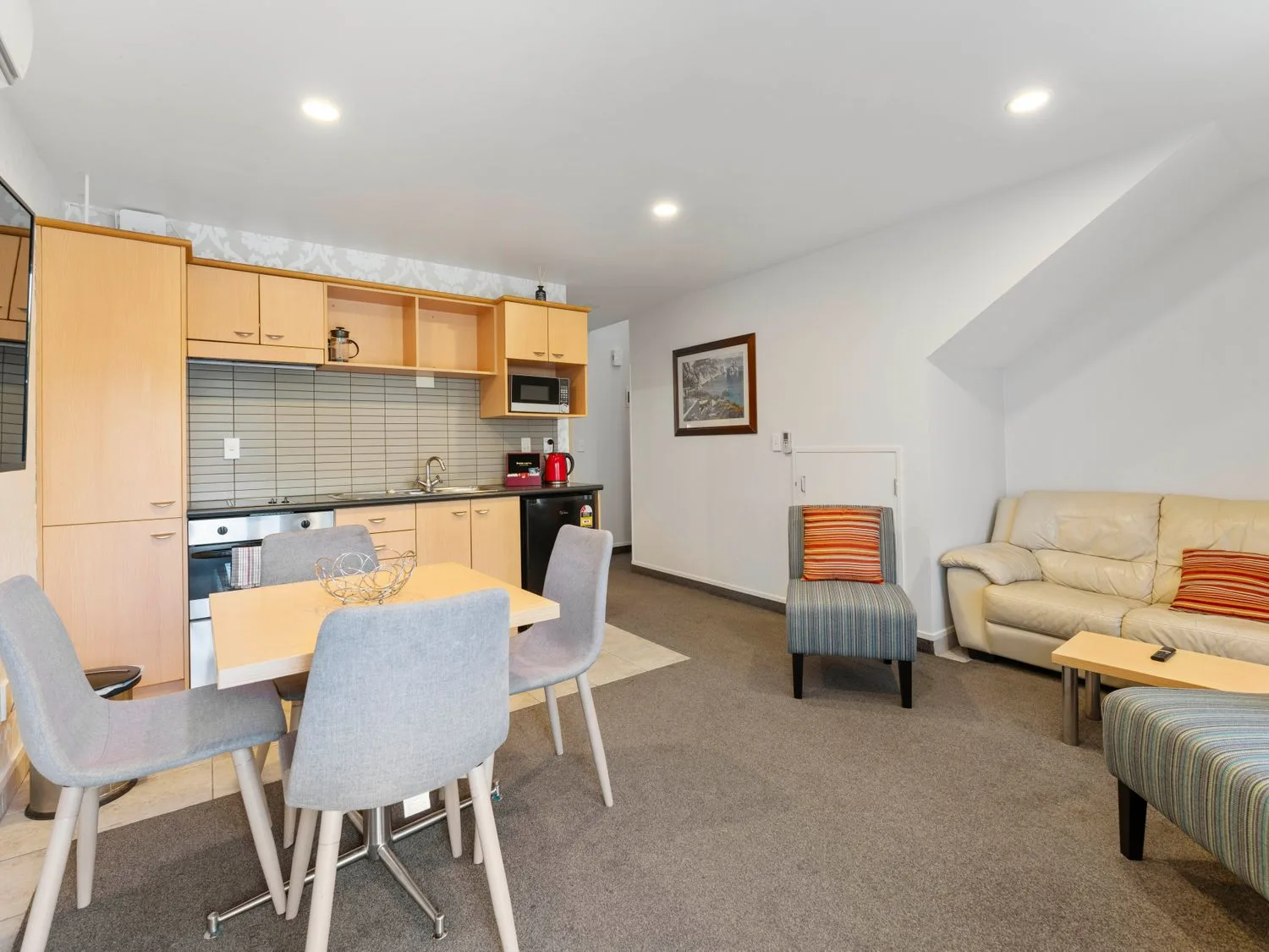 Una cocina y zona de estar con mesa de comedor y sillas, un sofá y sillones en Sun and Swim - Lake Taupo Holiday Home, en Taupo Central.