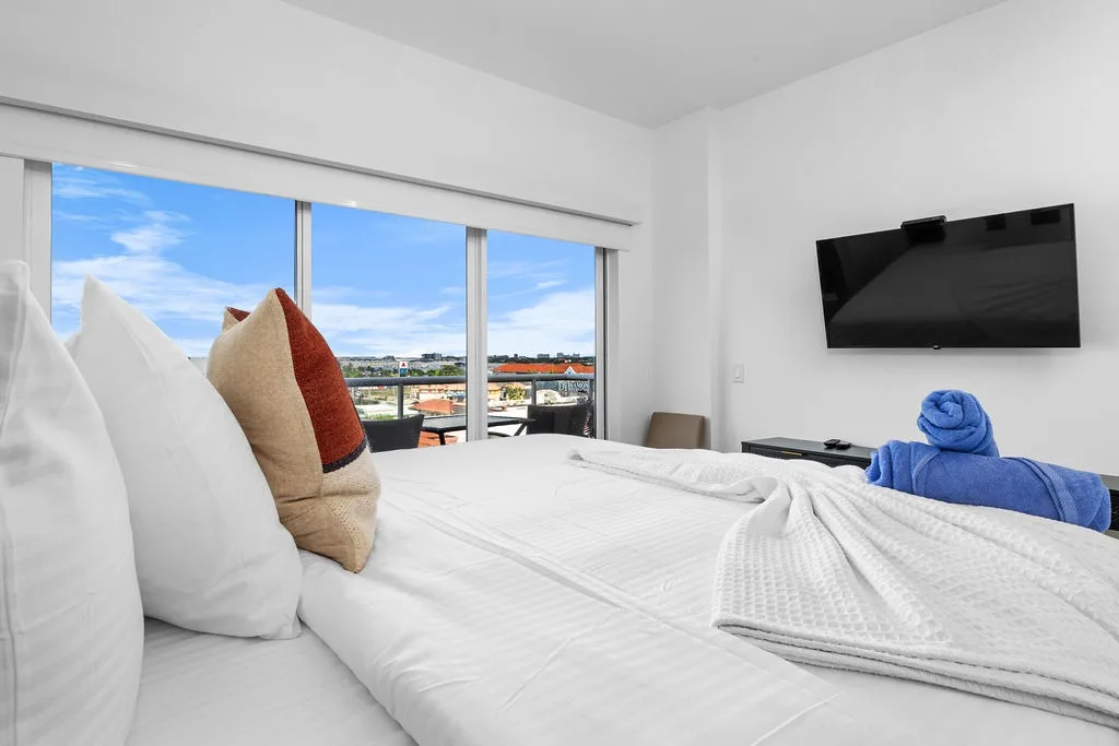 Settle into your bright, modern bedroom with a plush bed and crisp linens. Enjoy your morning coffee while taking in the city view through floor-to-ceiling windows, or unwind with a show on the wall-mounted TV.