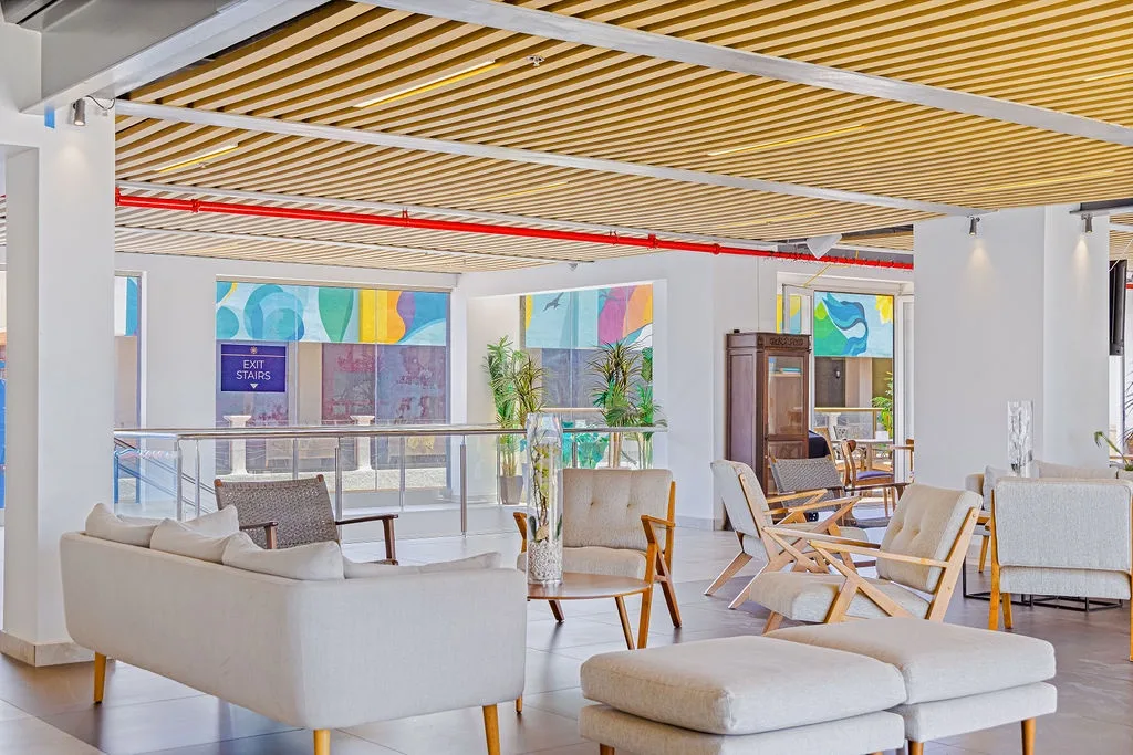 Bright, modern lobby featuring warm wood-slatted ceilings, contemporary seating, and vibrant local artwork—your welcoming arrival point to start your getaway.