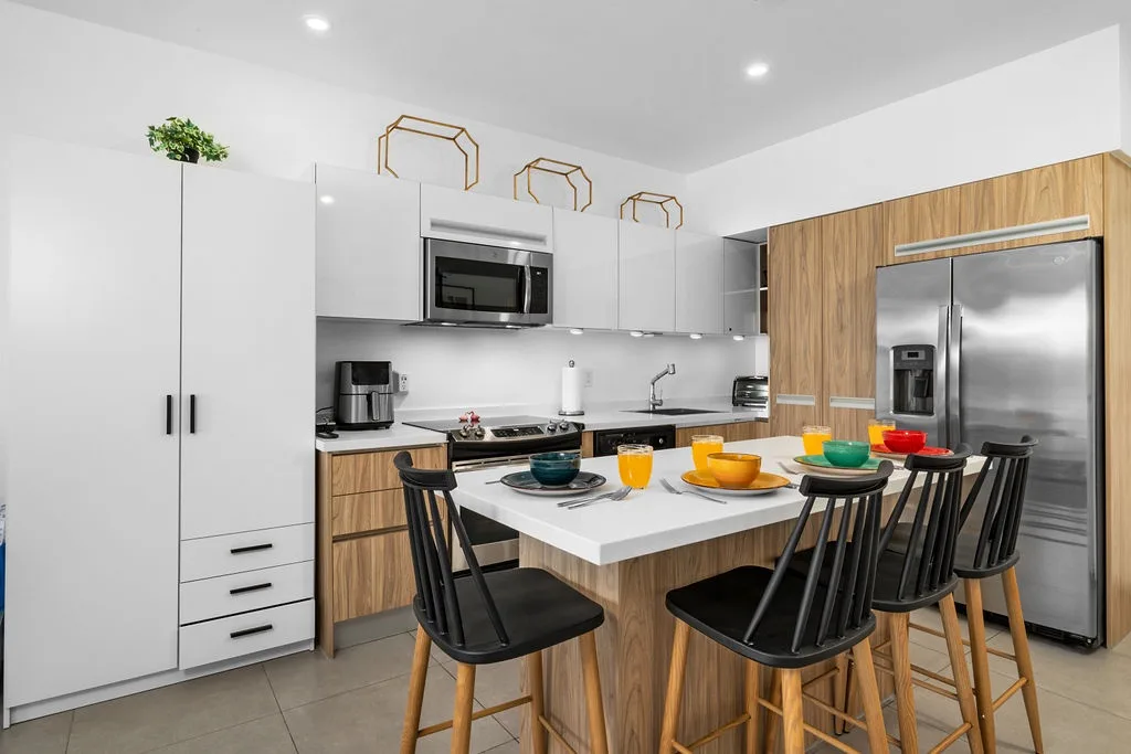 Modern, fully equipped kitchen featuring sleek stainless steel appliances, stylish wood-grain cabinetry, and an island with seating where you can gather for meals or conversation.