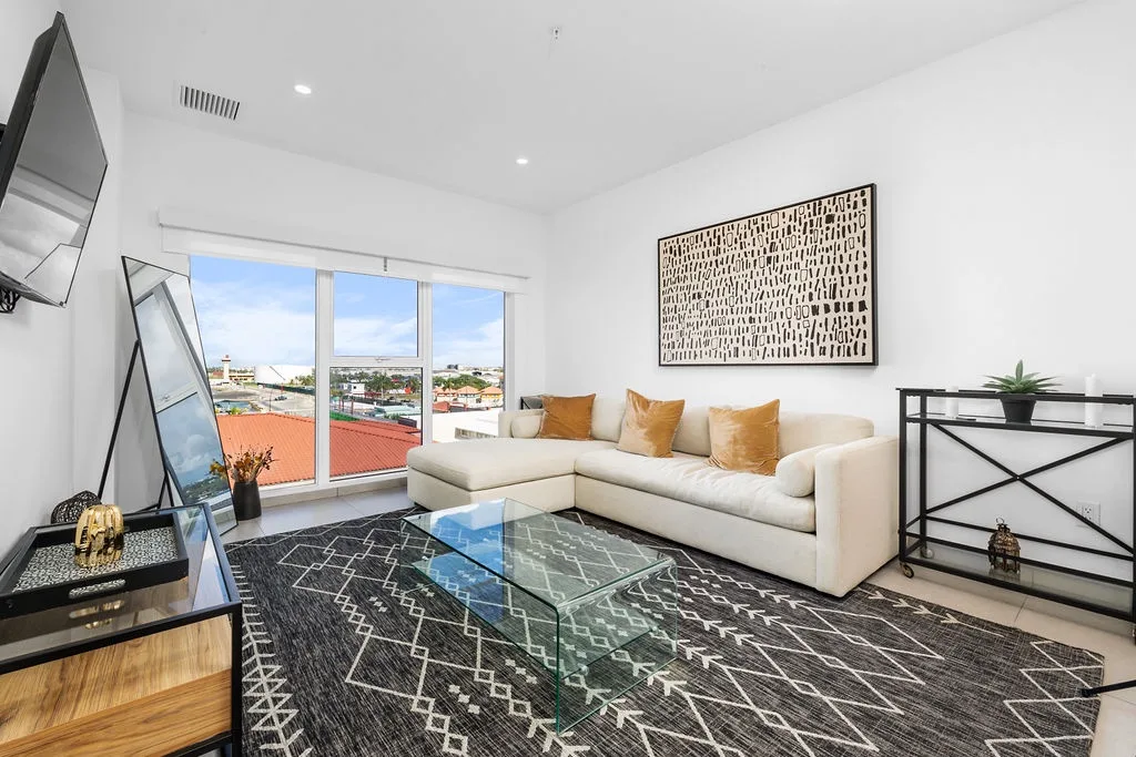 Relax in your bright, modern living room with a plush sofa, stylish decor, and a beautiful city view framing your peaceful retreat.