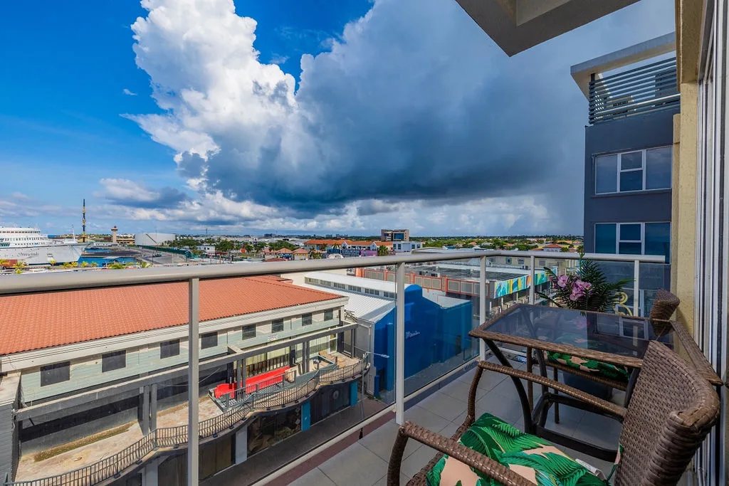 Settle into your private balcony with cozy wicker seating and sweeping city views. The spacious terrace overlooks the vibrant neighborhood below, perfect for morning coffee or evening relaxation.