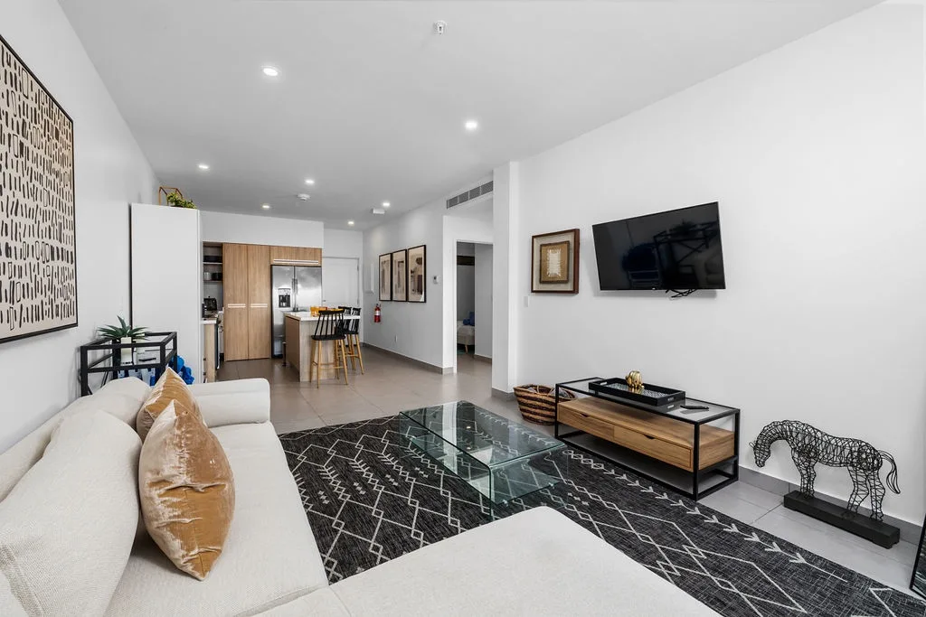 Your open-concept living area offers modern comfort with plush seating, a flat-screen TV, and stylish décor, while the sleek kitchen and dining space invite leisurely meals and relaxation.