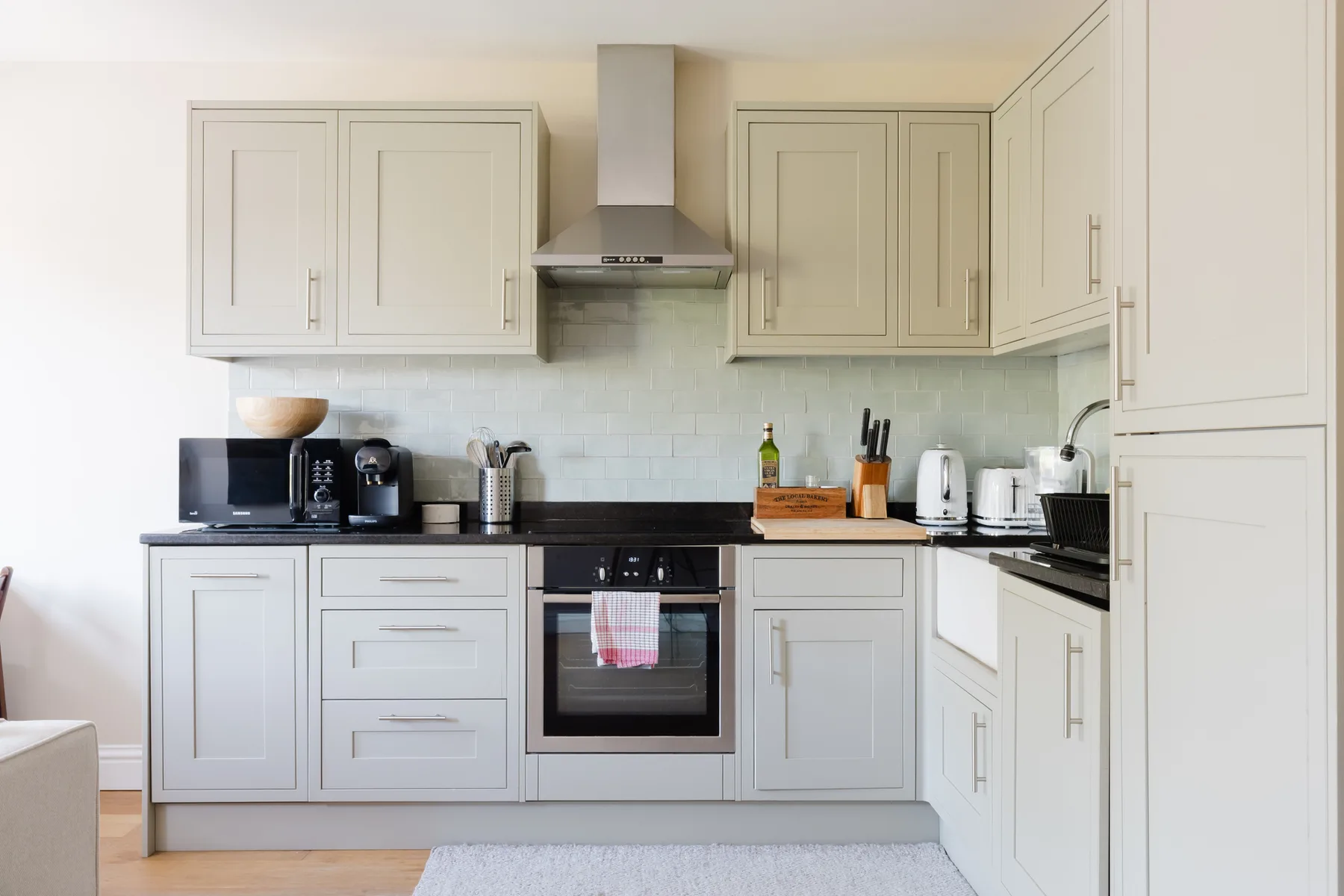 A bright kitchen with pale cabinets, a central oven, and countertop appliances.