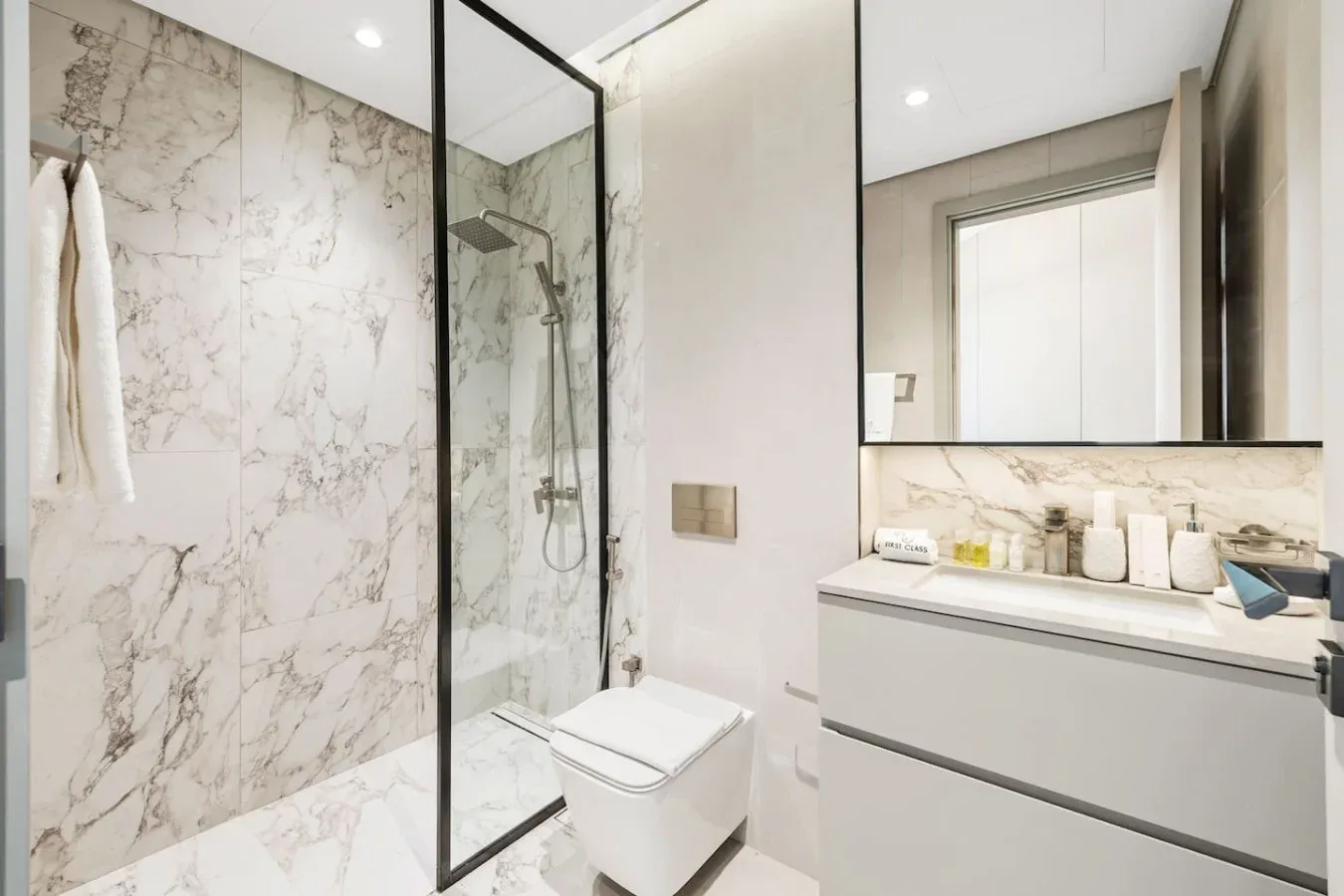 Un baño luminoso con ducha de vidrio, inodoro y lavabo amplio.