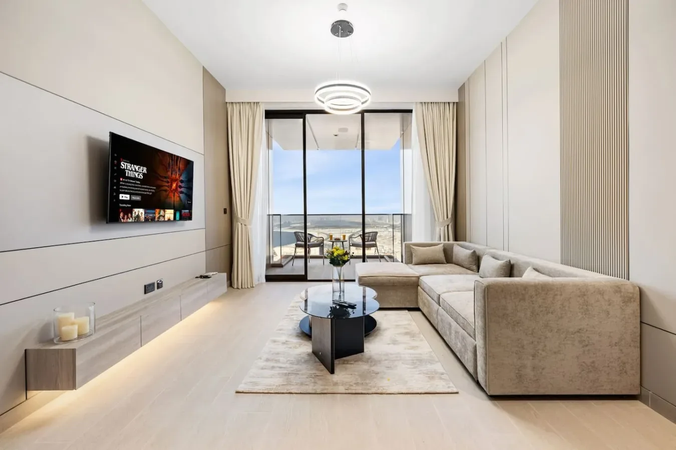 Una sala luminosa con un sofá seccional grande y puertas de vidrio que dan a un balcón.
