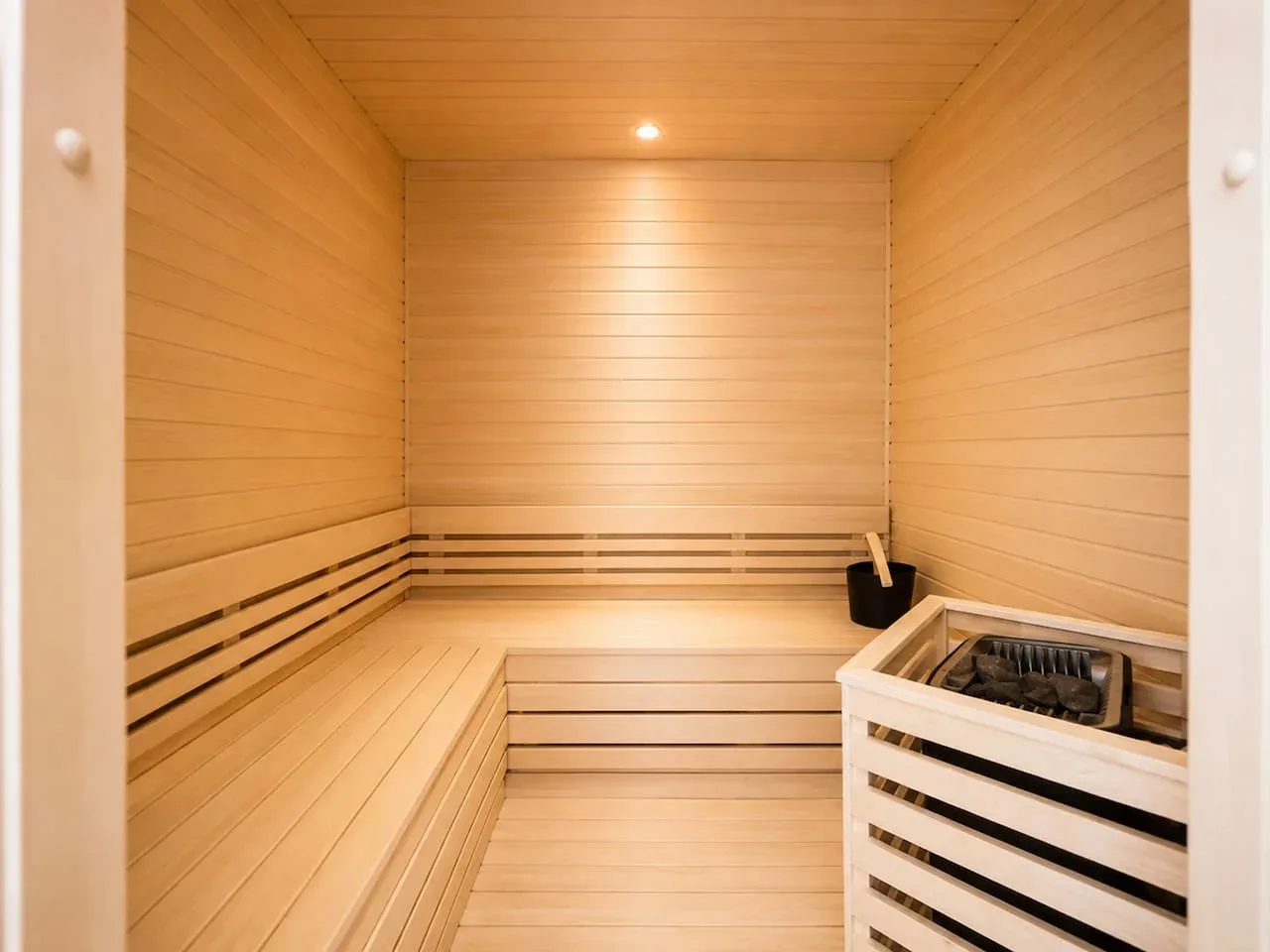 Una sauna de madera con bancos escalonados y un calentador.