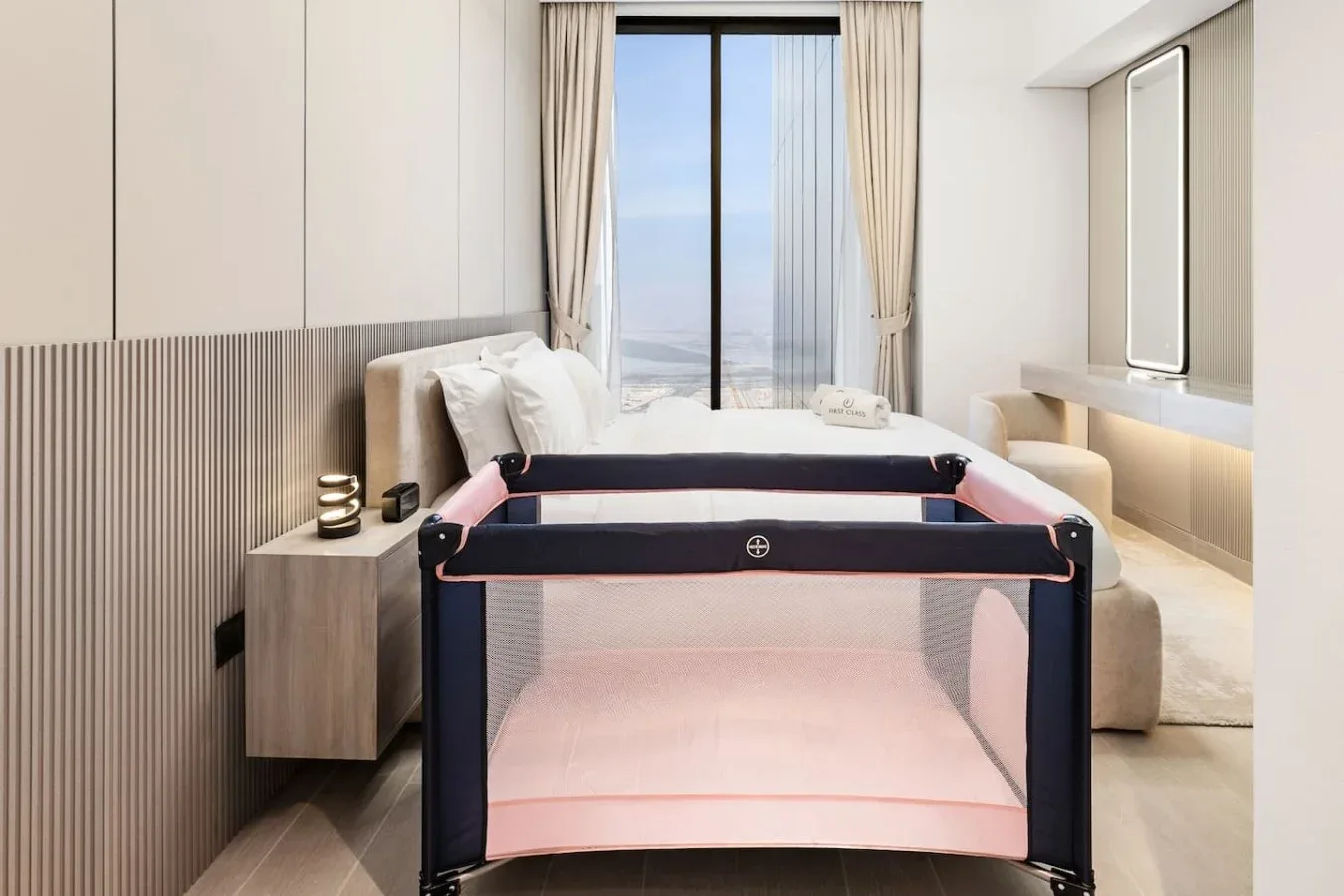 Un dormitorio con una cama y un corralito en primer plano.
