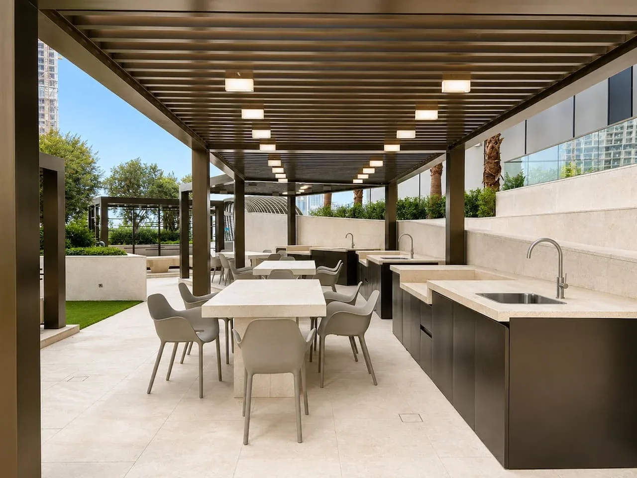 Zona de comedor exterior cubierta con mesas y una encimera con fregadero.
