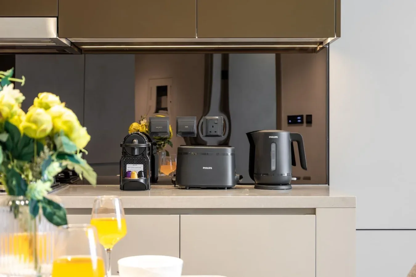Una encimera de cocina moderna con pequeños electrodomésticos y flores.