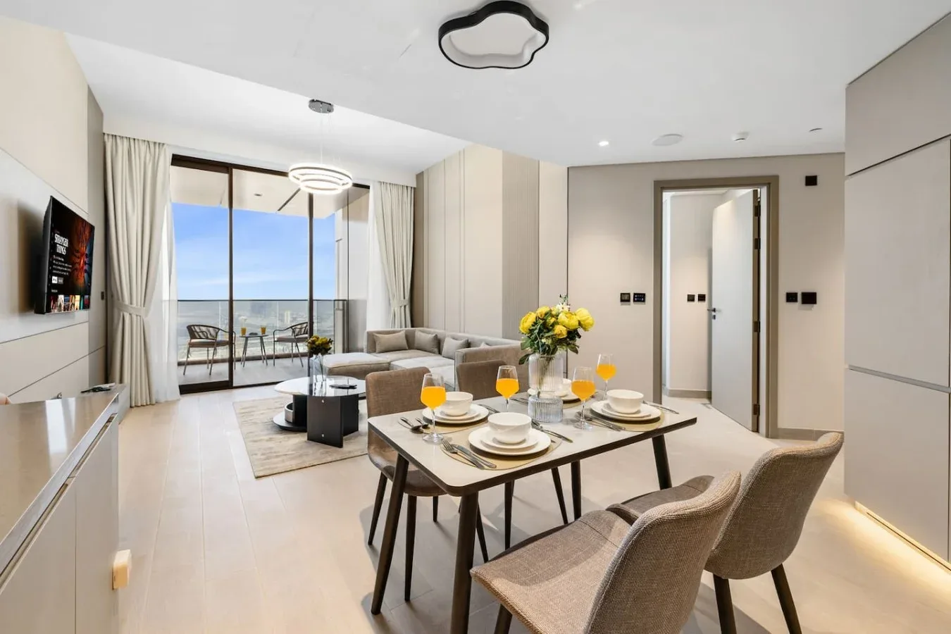 Una luminosa zona de comedor y estar con la mesa puesta y ventanales.