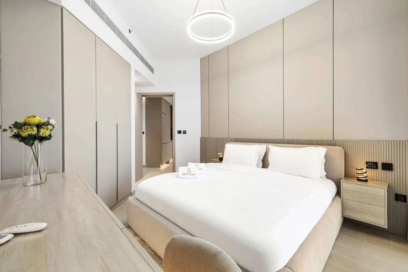 Un dormitorio moderno con una cama bien hecha y muebles en tonos claros y neutros.