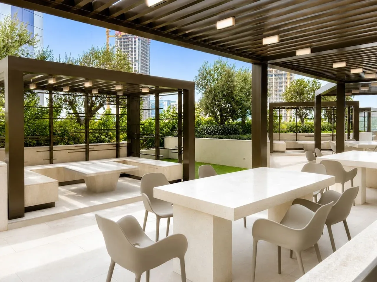 Comedor al aire libre con mesas y asientos bajo una pérgola.