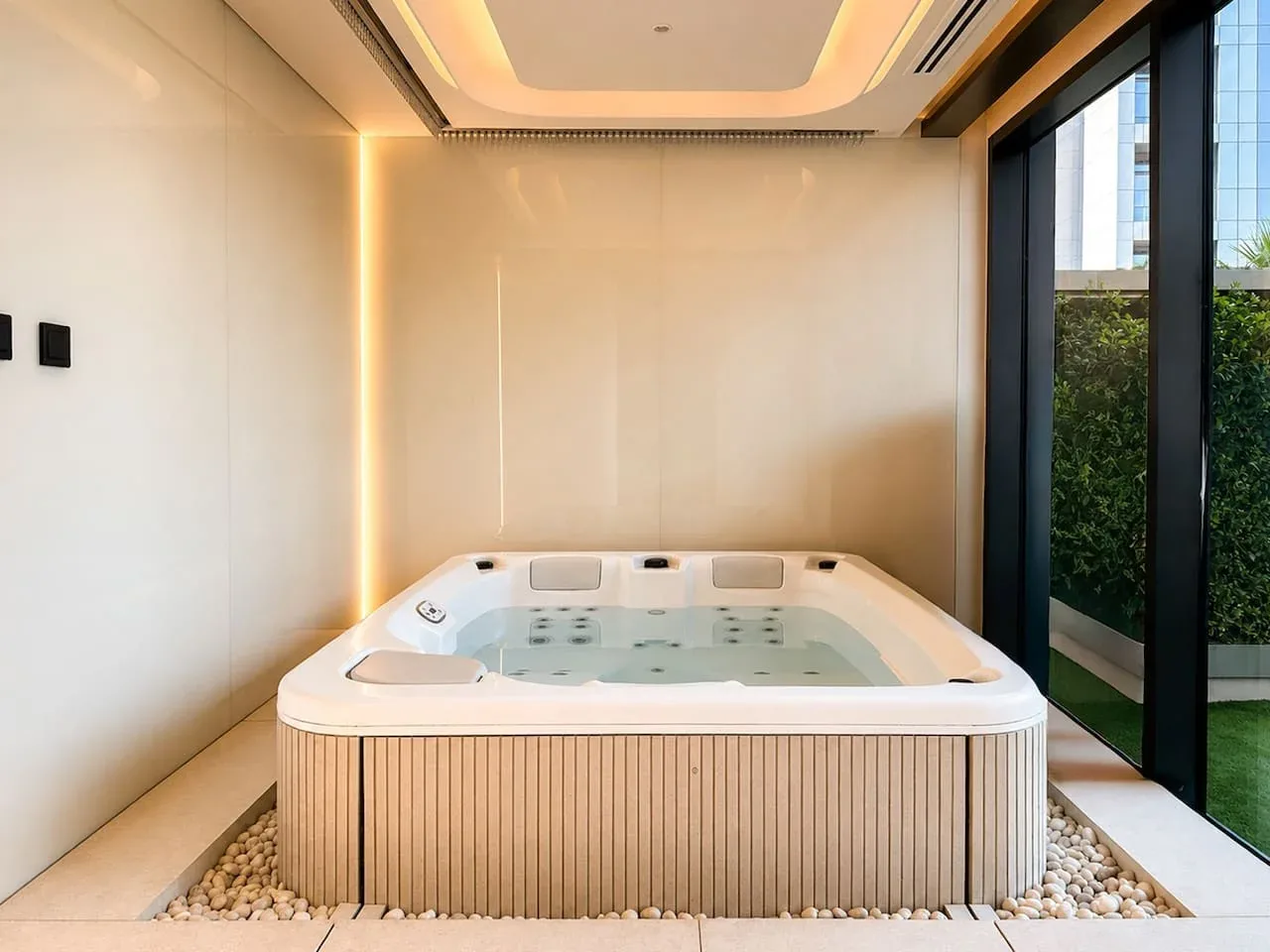 Un espacio de spa con una gran bañera de hidromasaje junto a ventanales.