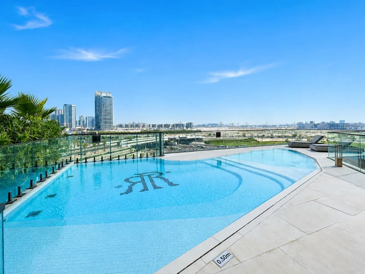 Una piscina en la azotea ofrece vistas del horizonte urbano bajo un cielo azul despejado.