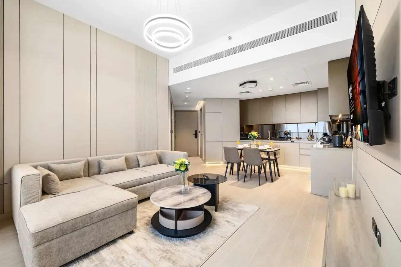 Una sala de estar con un sofá seccional y una cocina abierta al fondo.