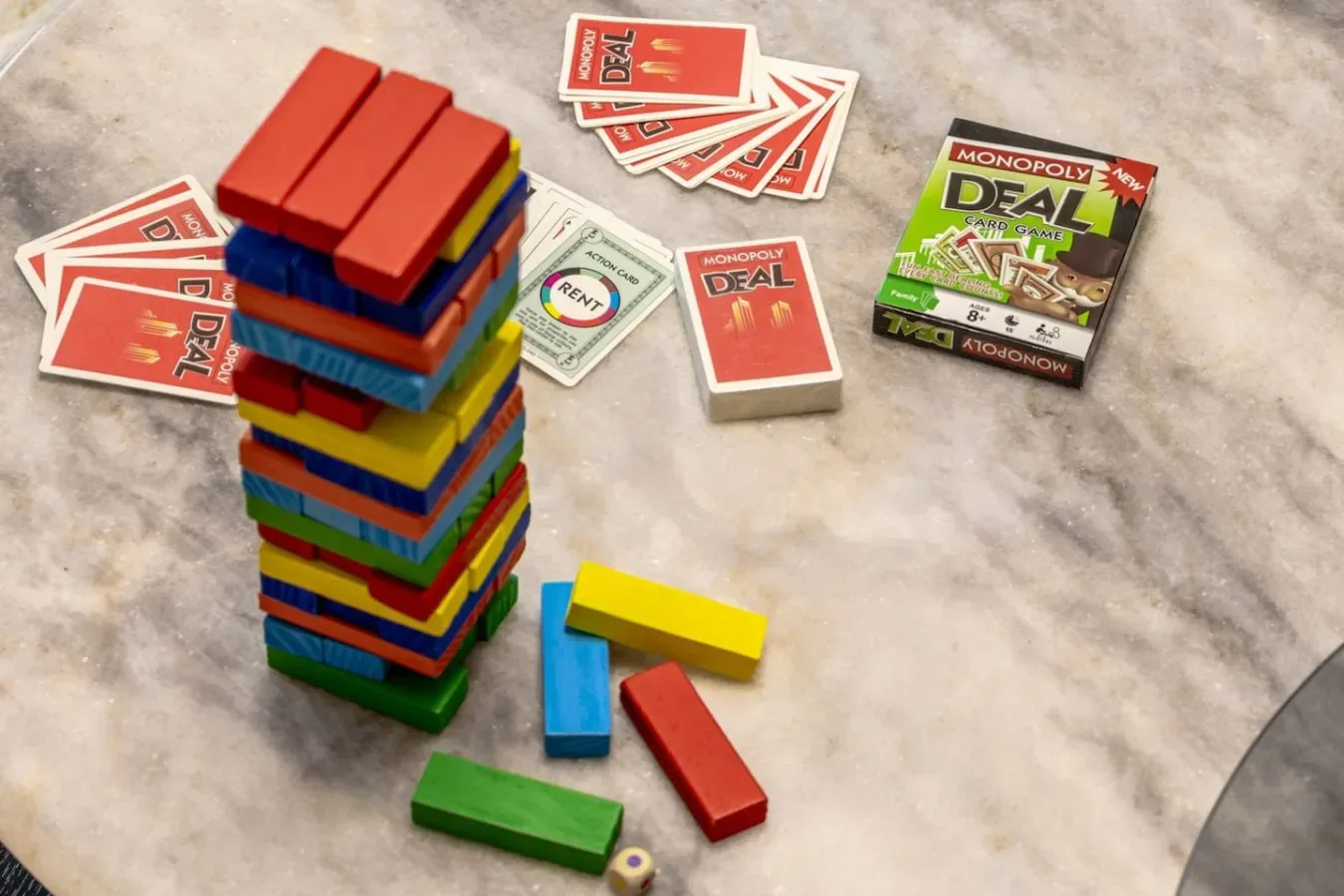 Una torre de bloques de colores está junto a cartas y bloques sueltos sobre una mesa.
