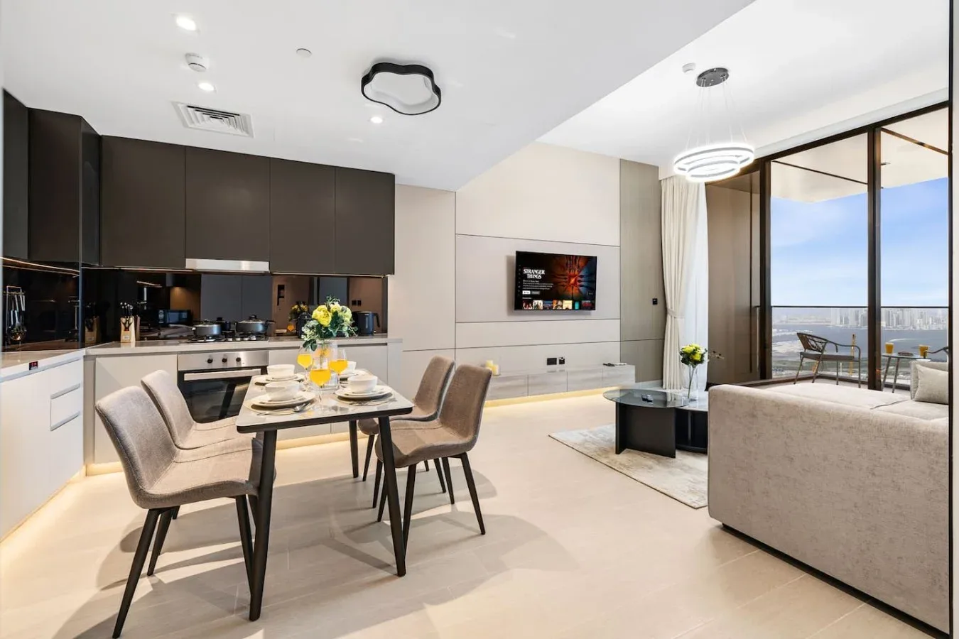 Sala de estar y comedor de planta abierta, con cocina y grandes ventanas.