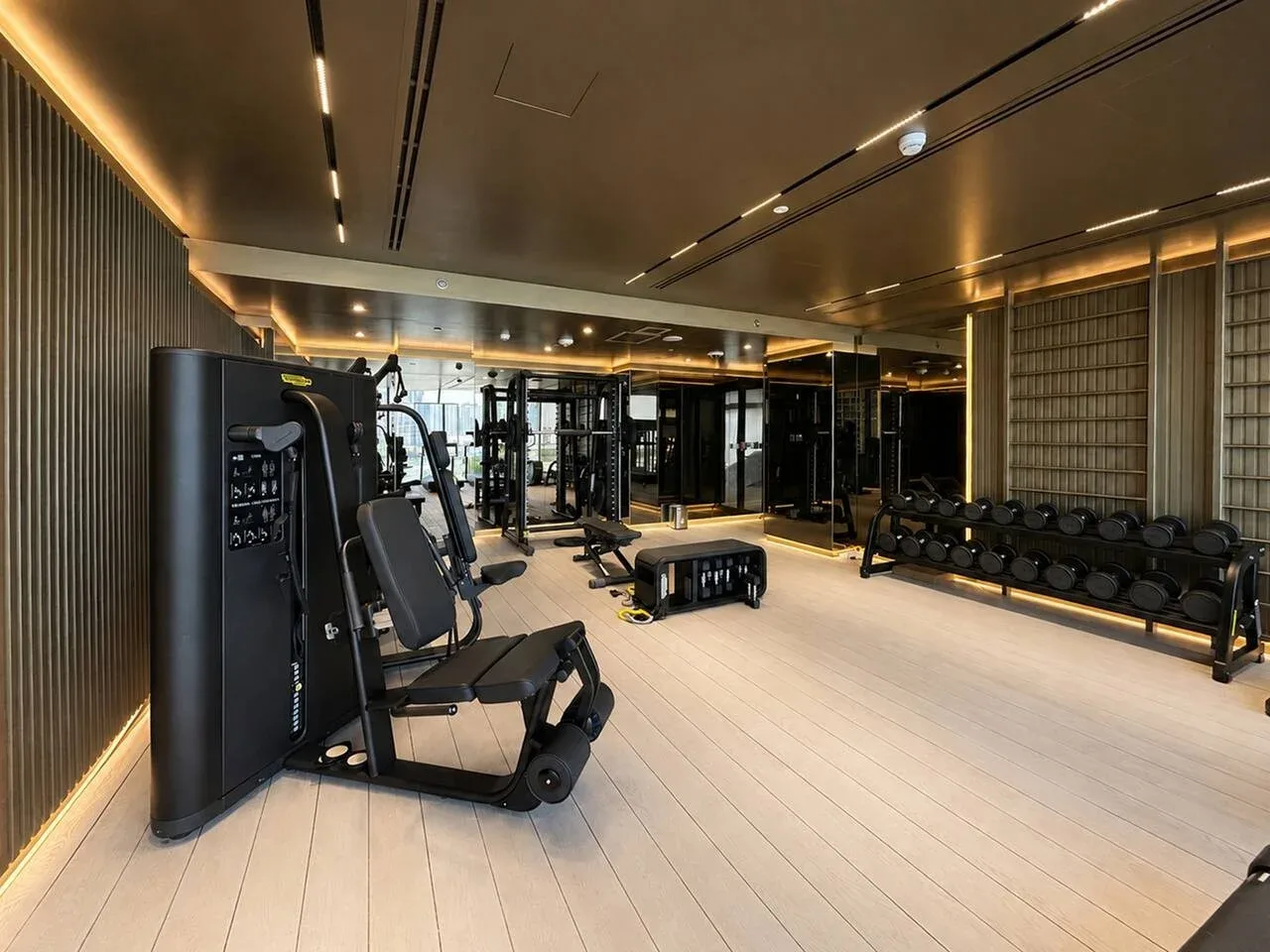 Un gimnasio moderno con máquinas de ejercicio, pesas y una iluminación intensa.