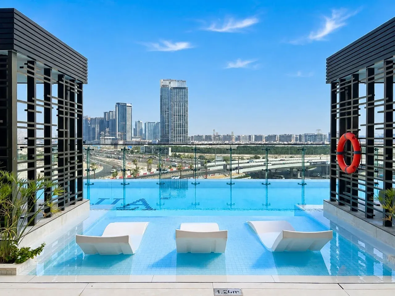 Una piscina en la azotea ofrece vistas del horizonte de la ciudad bajo un cielo azul despejado.