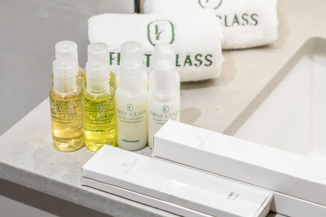 Tocador de baño con botellas de artículos de aseo, productos empaquetados y toallas dobladas.