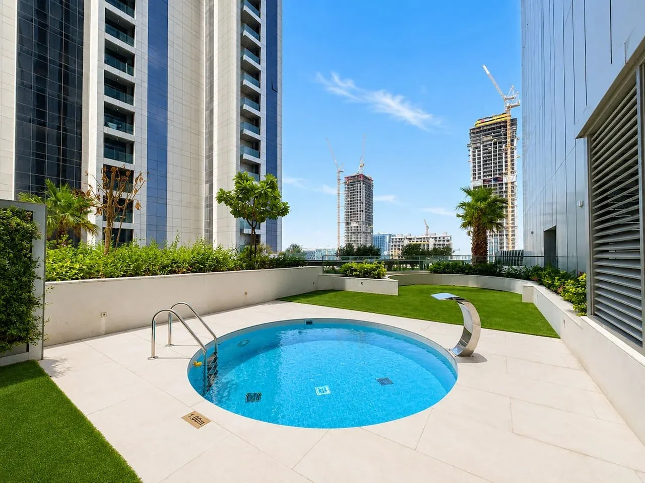 Una piscina en la azotea está junto a una terraza pavimentada y un pequeño césped.