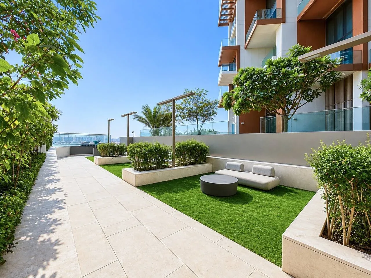 Una terraza ajardinada cuenta con un sendero pavimentado, césped y asientos.