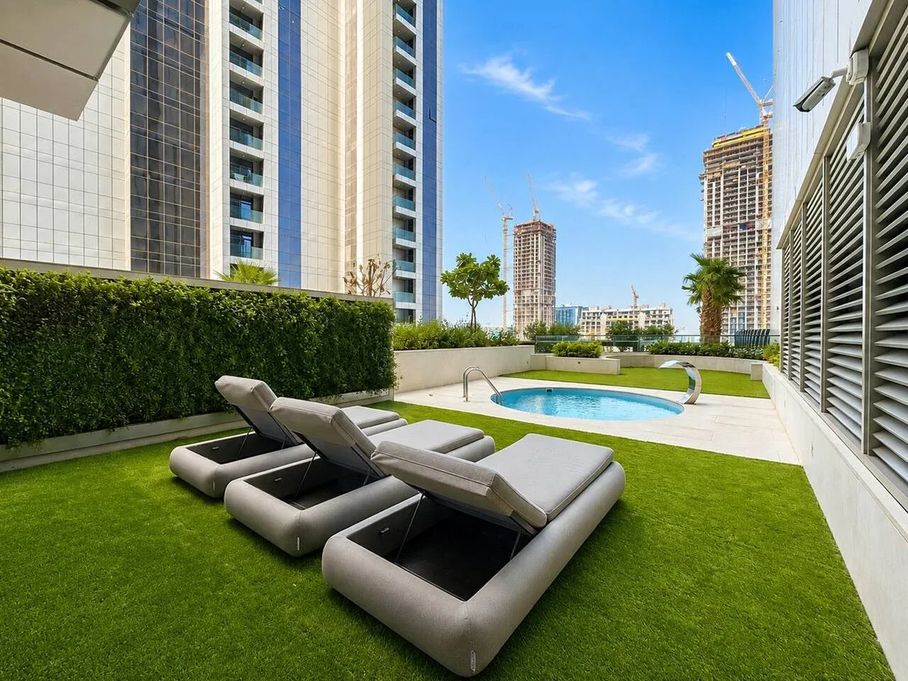 Una terraza en la azotea con asientos, césped artificial y una piscina pequeña.