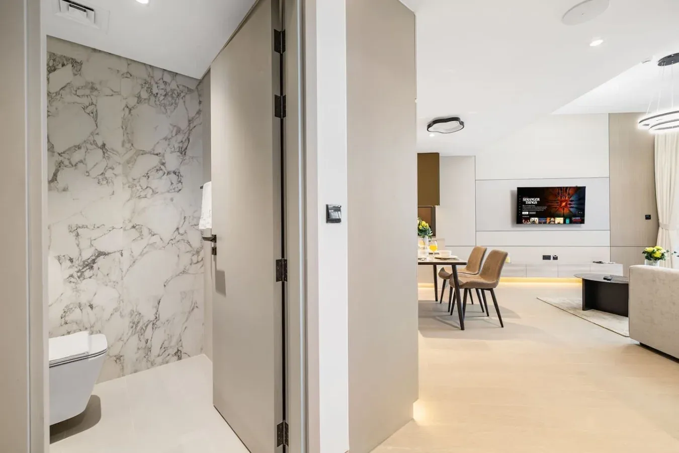 Un interior moderno y luminoso con un baño junto a una sala de estar y comedor.