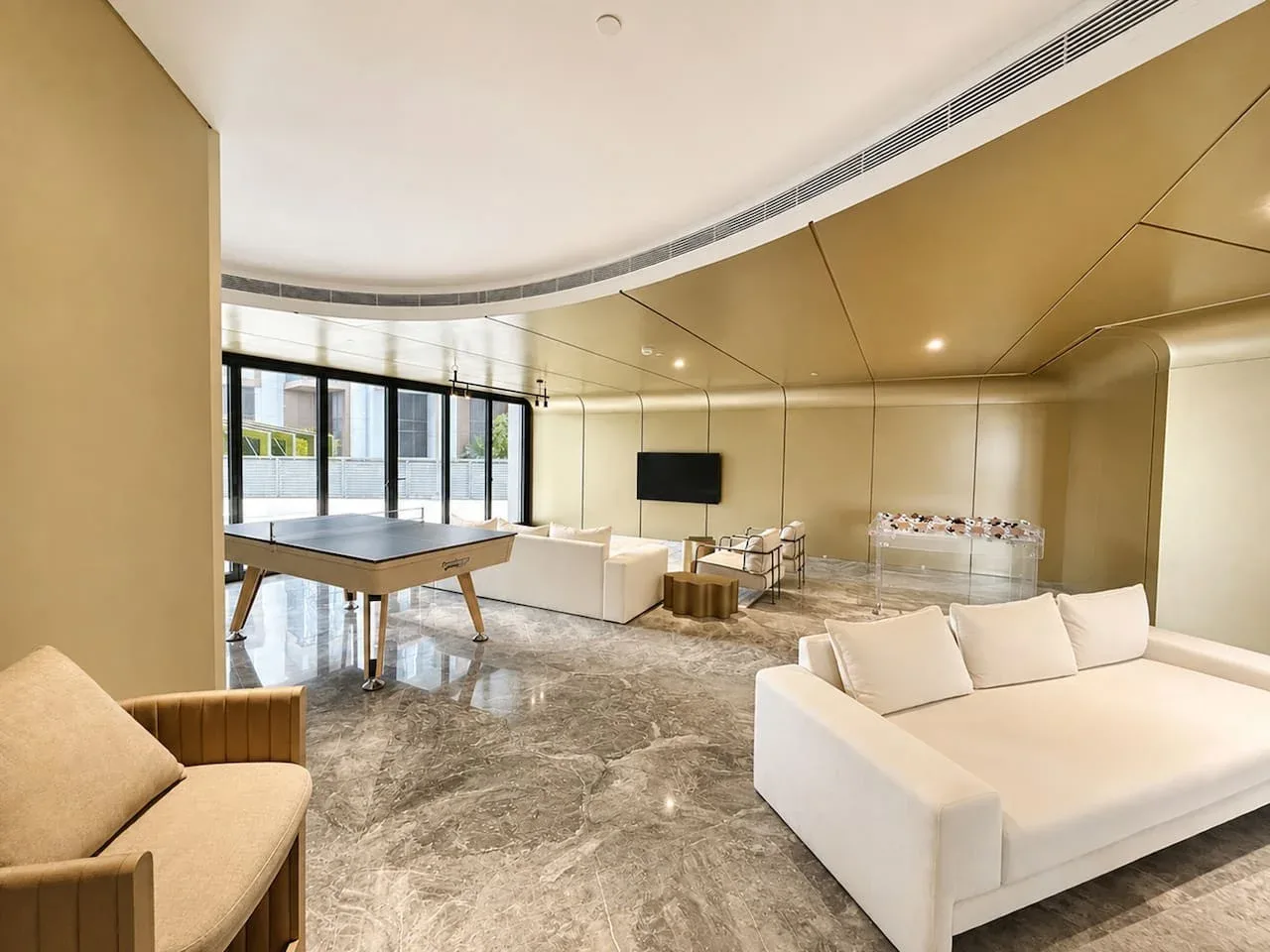 Una sala moderna con asientos blancos, un televisor y una mesa baja.