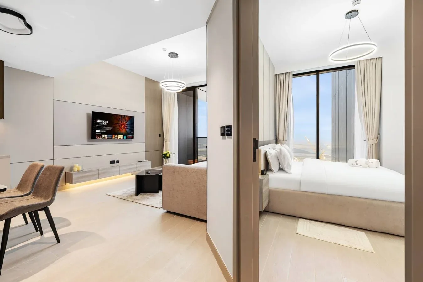 Un dormitorio moderno se abre a una zona de estar, con una ventana grande junto a la cama.