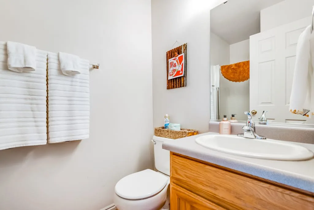 Un baño con lavabo, inodoro y toallas colgadas en la pared.