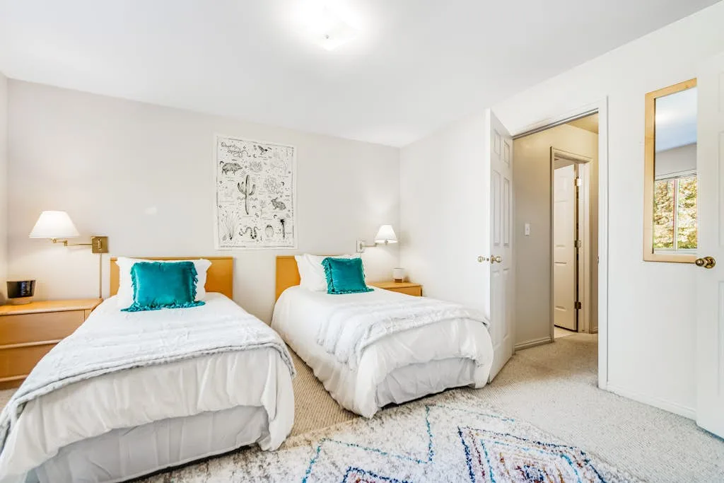 Un dormitorio luminoso con dos camas y lámparas de noche.