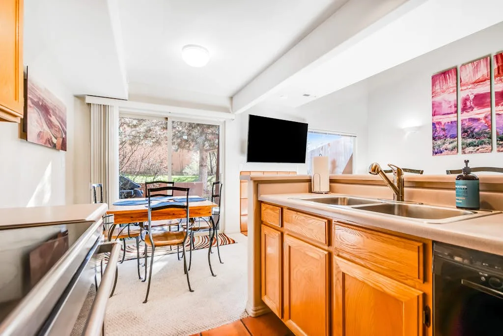 Una cocina luminosa con una mesa de comedor junto a grandes ventanas.