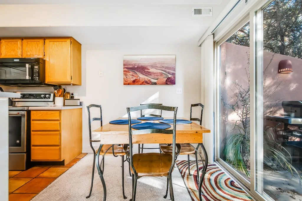 Un comedor con una mesa de madera y sillas junto a grandes puertas de vidrio.