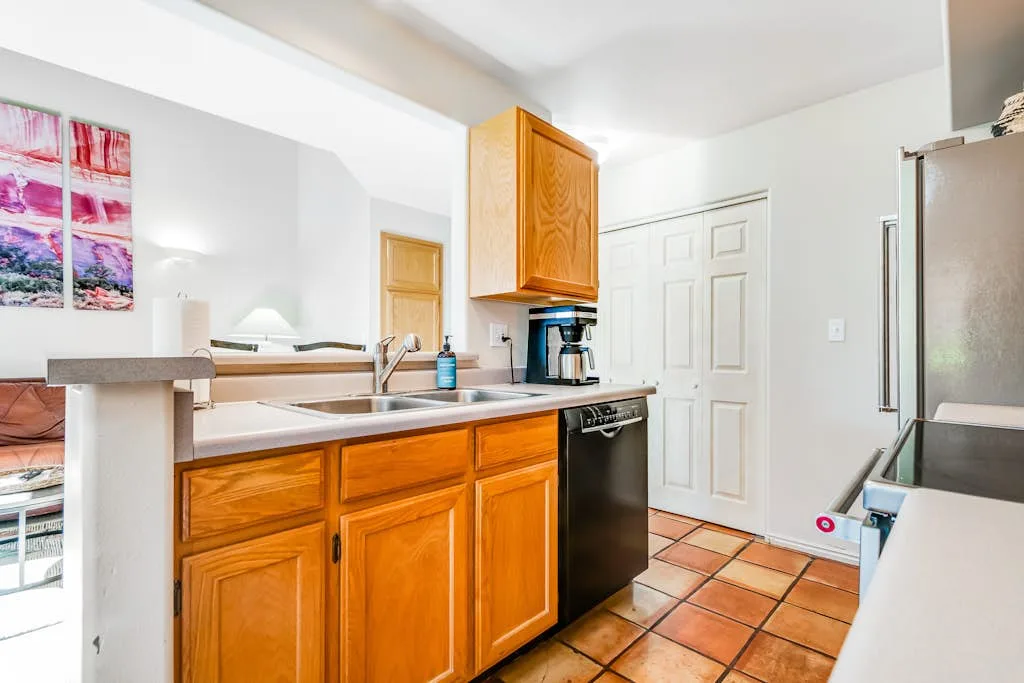 Una cocina luminosa con gabinetes de madera, fregadero y piso de baldosas.