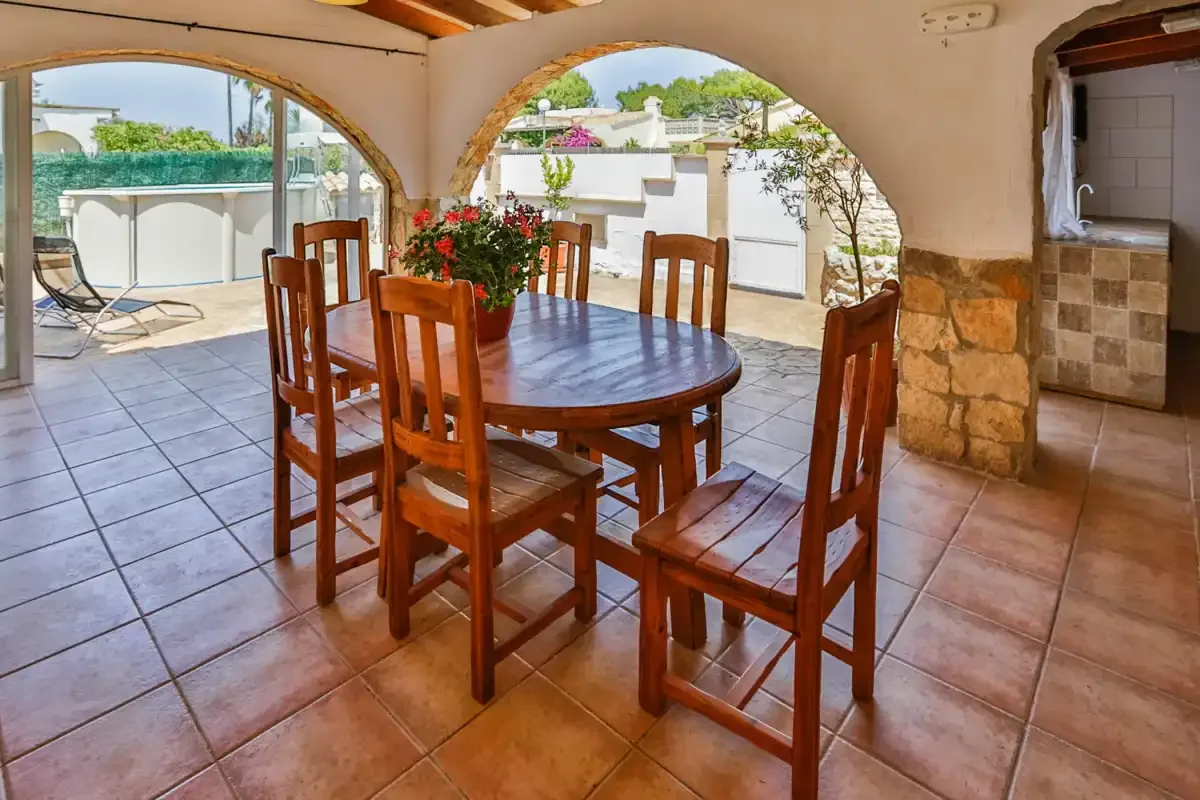 A dining area with a wooden table and chairs beside arched openings.