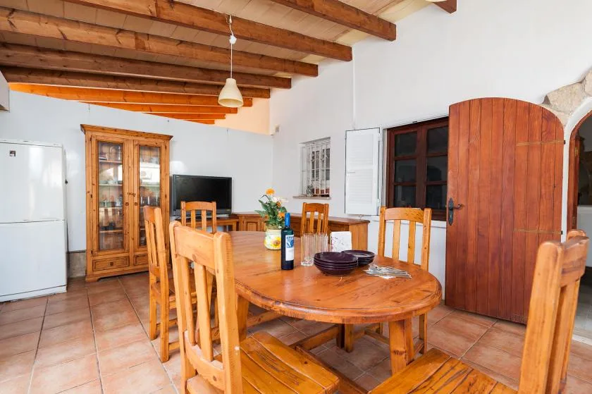 A dining area with a wooden table and chairs beneath exposed ceiling beams.