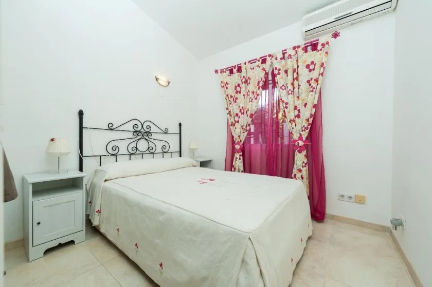 A bedroom with a bed, bedside table, and floral curtains.