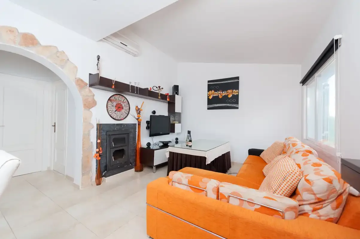A bright living room with orange seating and a fireplace.