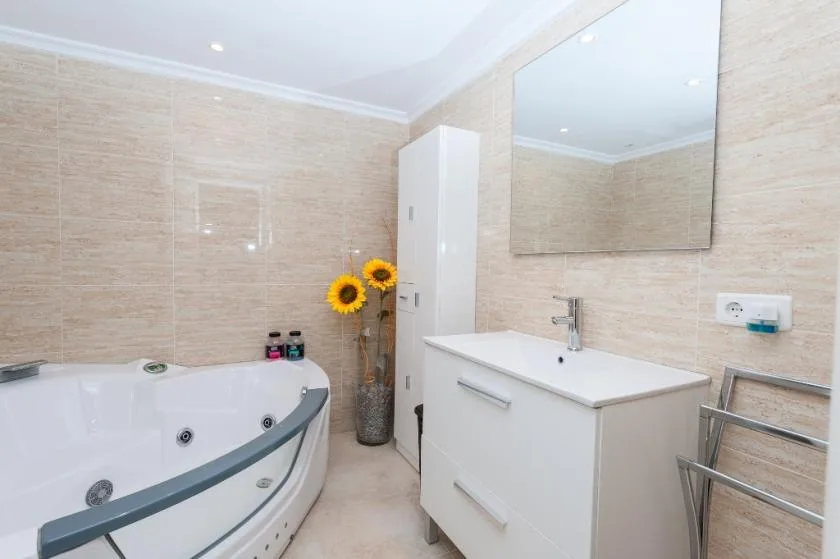 A bright bathroom with a corner bathtub and a white vanity.