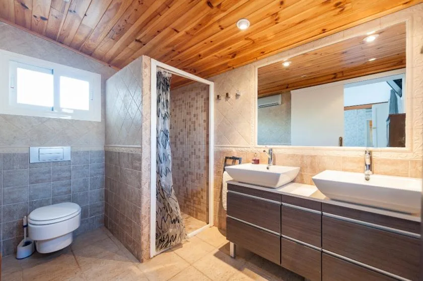 A tiled bathroom with a shower, toilet, and double vanity.