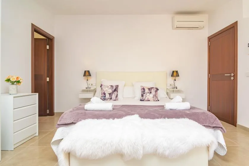 A bedroom with a neatly made bed and two bedside lamps.