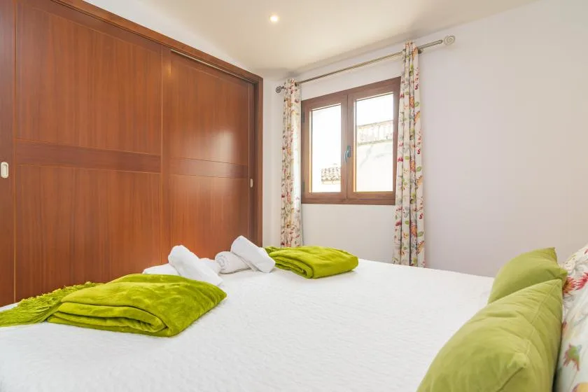 A bedroom with a large bed dressed in white and green linens.