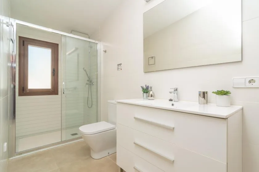 A bright bathroom with a glass shower and a white vanity.