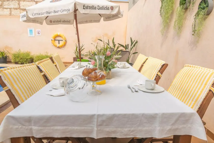 An outdoor dining table is set beneath a patio umbrella, with striped seating.
