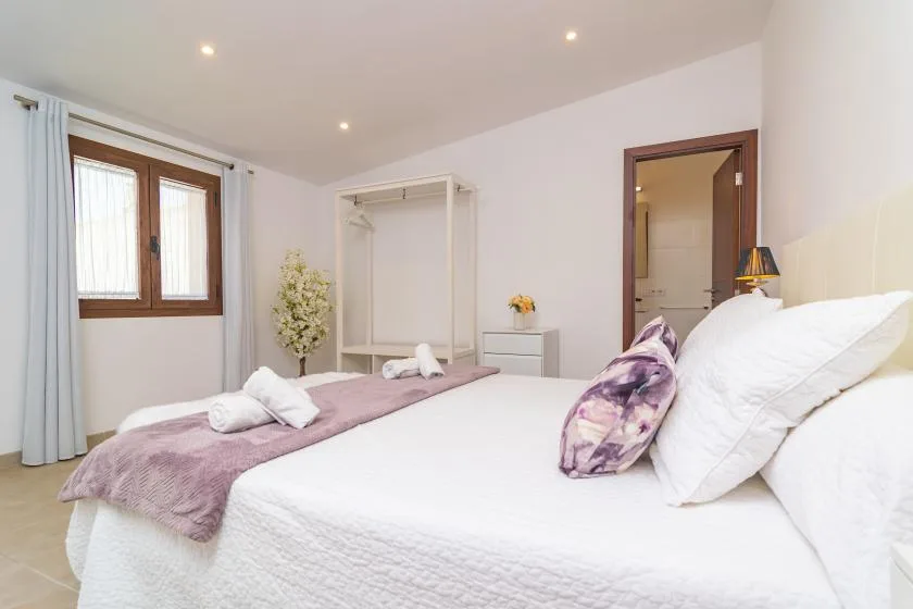 A bright bedroom with a large bed and a window with curtains.