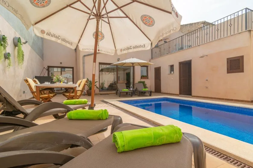 A pool courtyard with lounge seating and a large shade umbrella.
